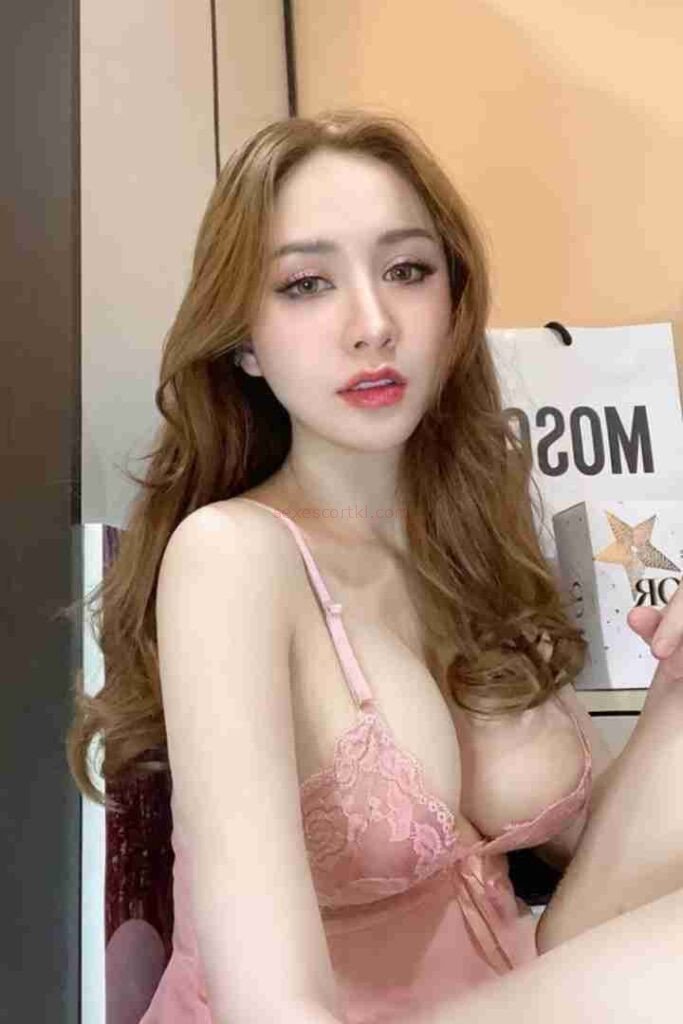 Attractive Asian woman in pink lingerie. Call girl Nin, with long brown hair.