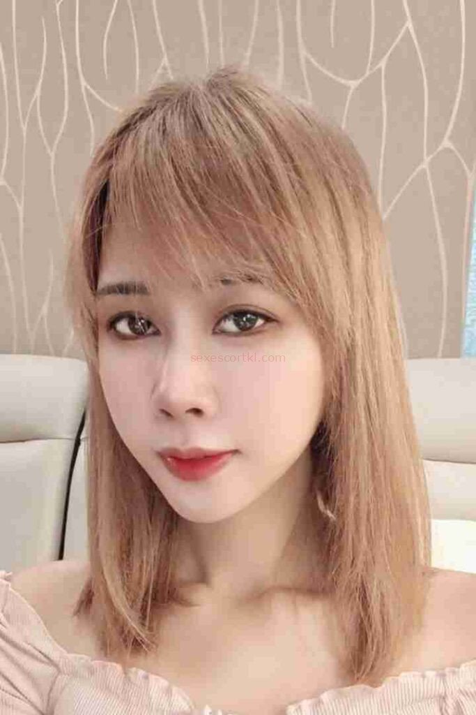 Lienna, a woman with blonde hair and red lipstick, posing indoors. Escort Girl Services.