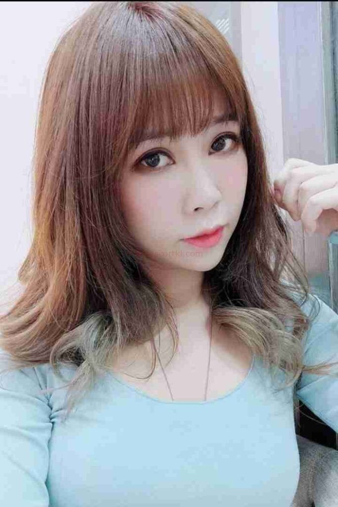 Lienna Escort Girl with brown hair and bangs, wearing a light blue top.