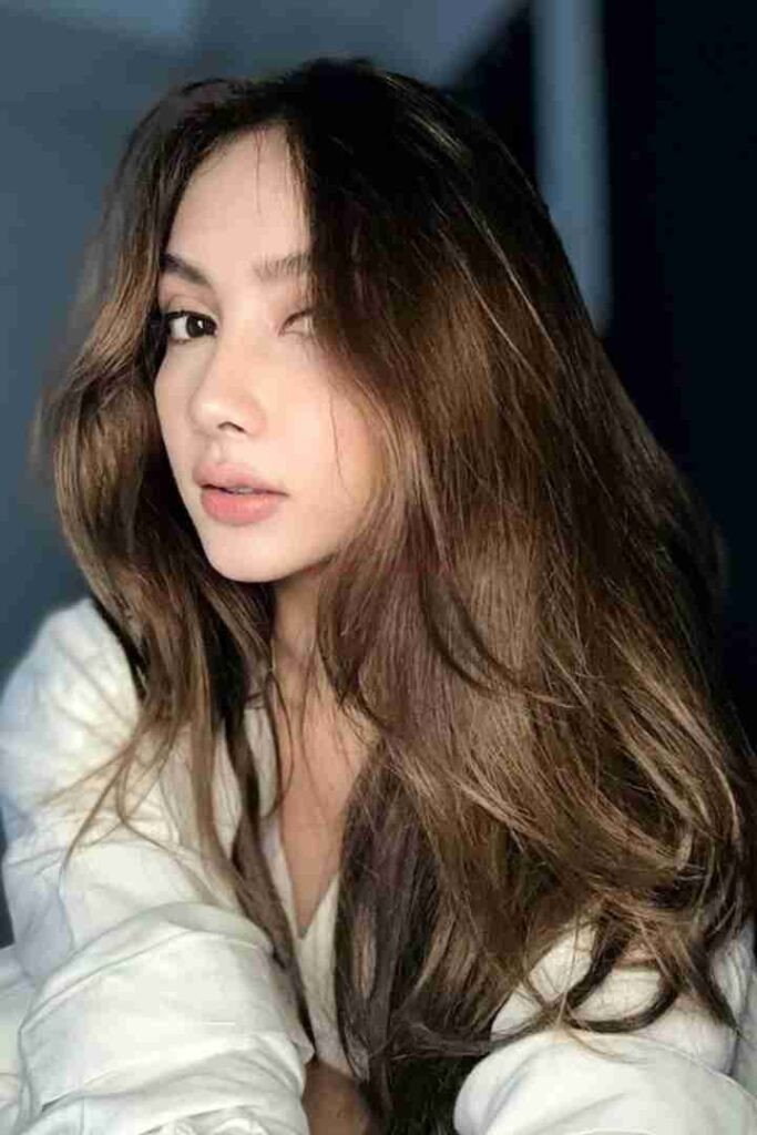 Beautiful Malay woman Zulla with long brown hair and a white top.