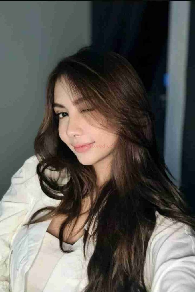 Attractive Malay woman winking, wearing white top. Zulla Malay Escort.