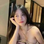 Asian woman with long dark hair resting her head on her hand at a table.