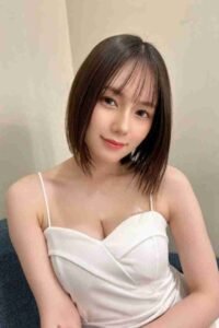 Smiling Asian woman with short bob haircut wearing white dress. Portrait of a beautiful young woman.