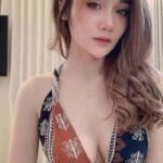 Beautiful Asian woman with long wavy hair wearing a patterned halter top. Portrait shot.