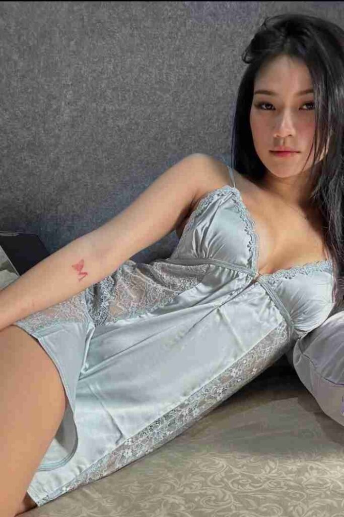 Woman in blue lingerie lying on bed, looking at camera