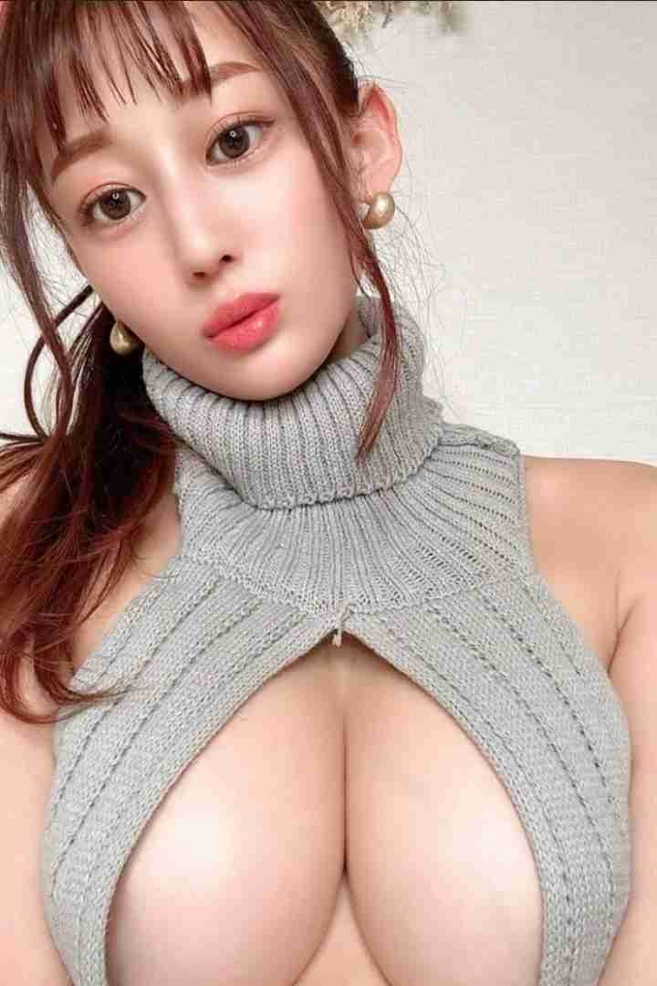 Attractive woman with brown hair wearing a gray virgin killer sweater and gold earrings, looking at the camera.