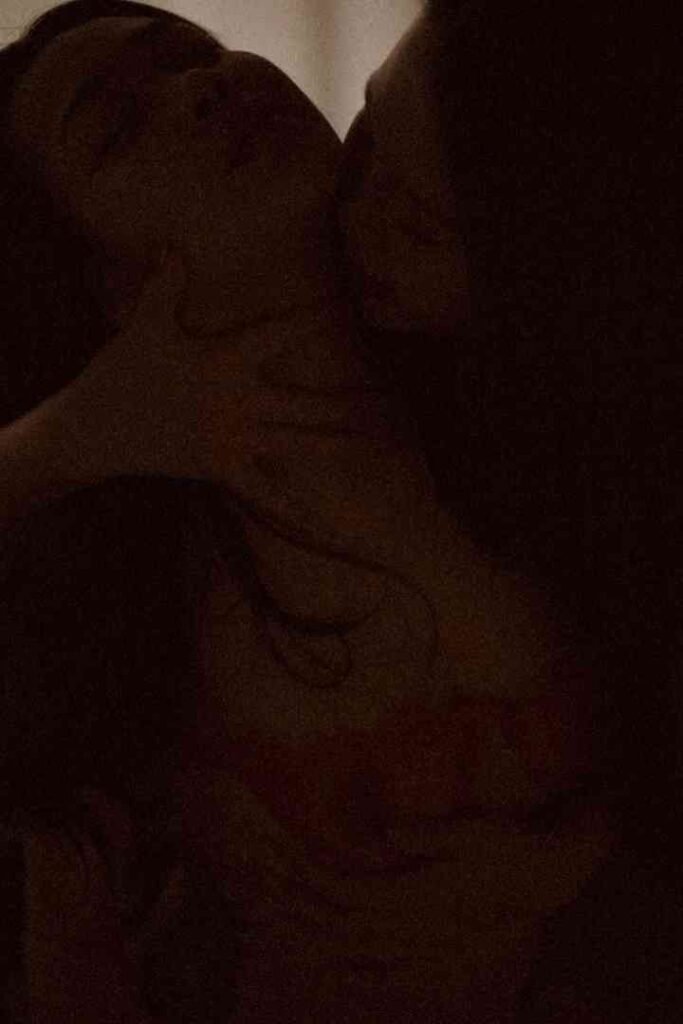 Intimate moment between two people, one kissing the other's neck.