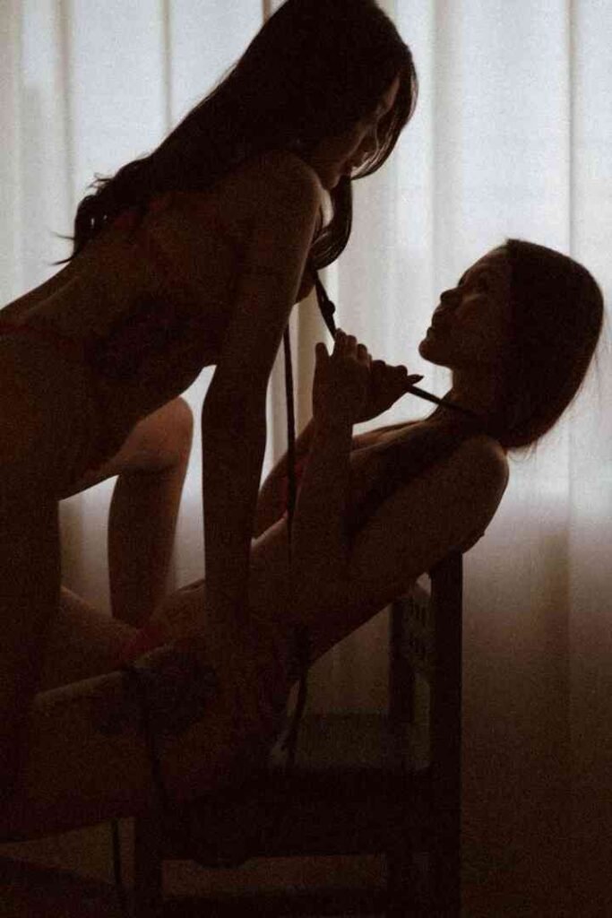 Two women in lingerie with one holding a rope and both looking at each other