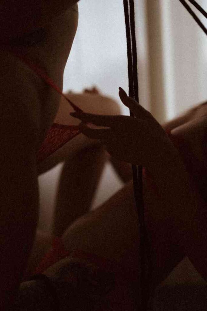 Close-up of a woman's hand holding a rope in a dimly lit room