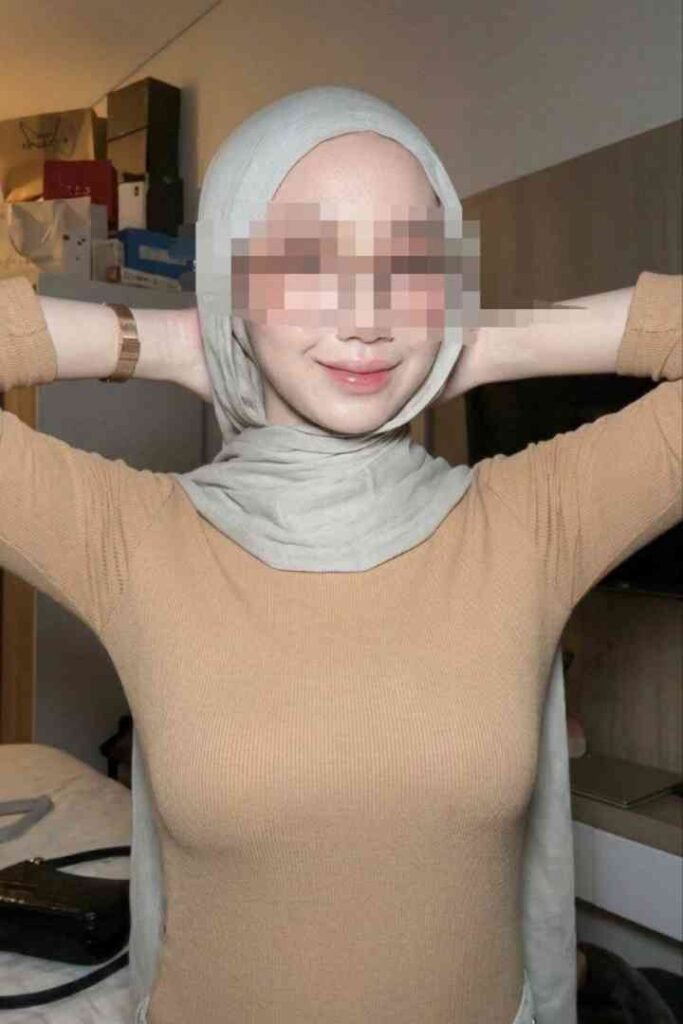 Sex Escort KL Girl Kesya, a Malay call girl in Kuala Lumpur, smiling and posing with her hands on her head Incall & Outcall Escorts Girl Service